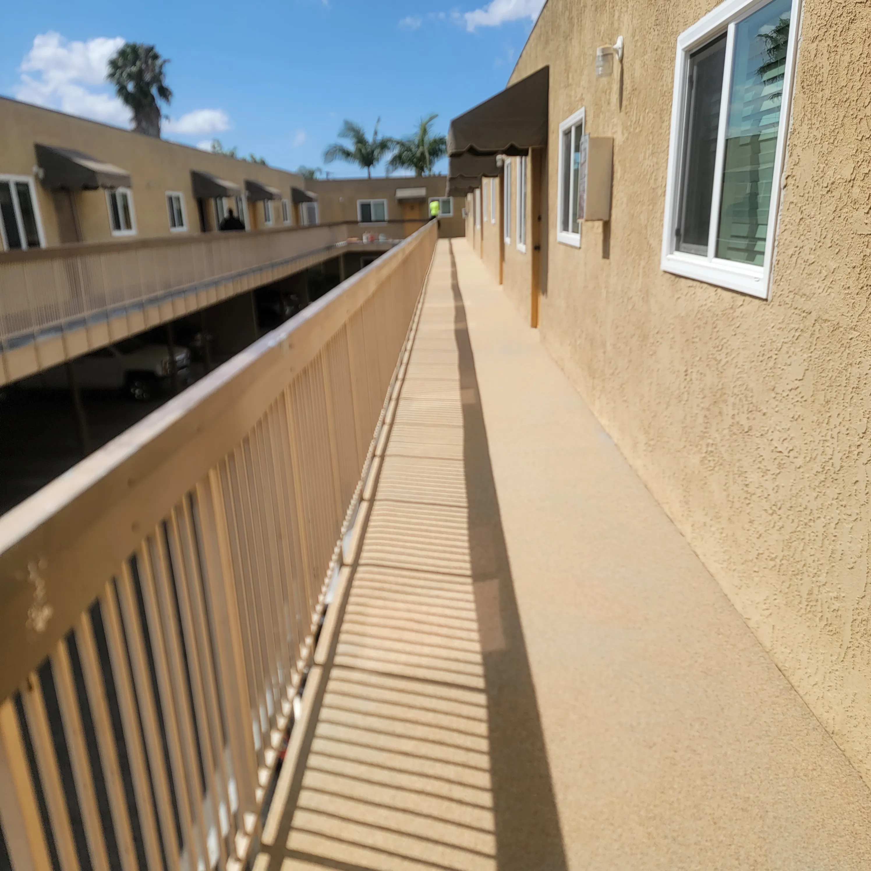 Professional waterproofing team repairing a cantilevered balcony on a modern apartment building in Orange County